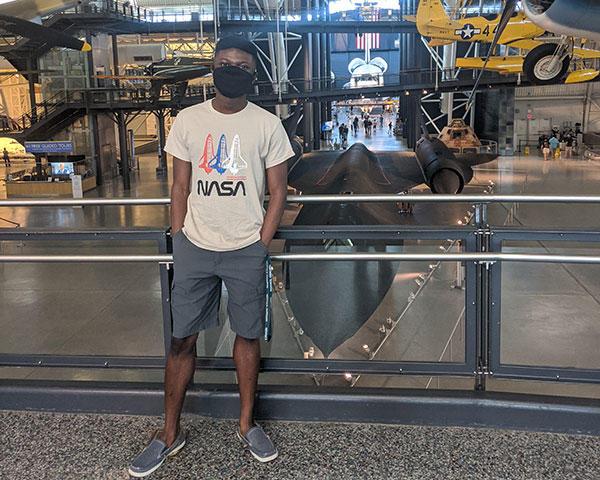 Sidney Boakye standing in the space museum in a NASA t-shirt. 