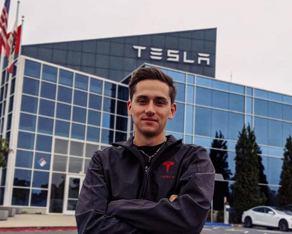 Daniel Scott Mitchell standing in front of the Tesla headquarters on a gloomy day.