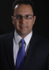 Ali Beheshti wears a dark suit, blue tie, and glasses in his faculty profile for the Department of Mechanical Engineering.